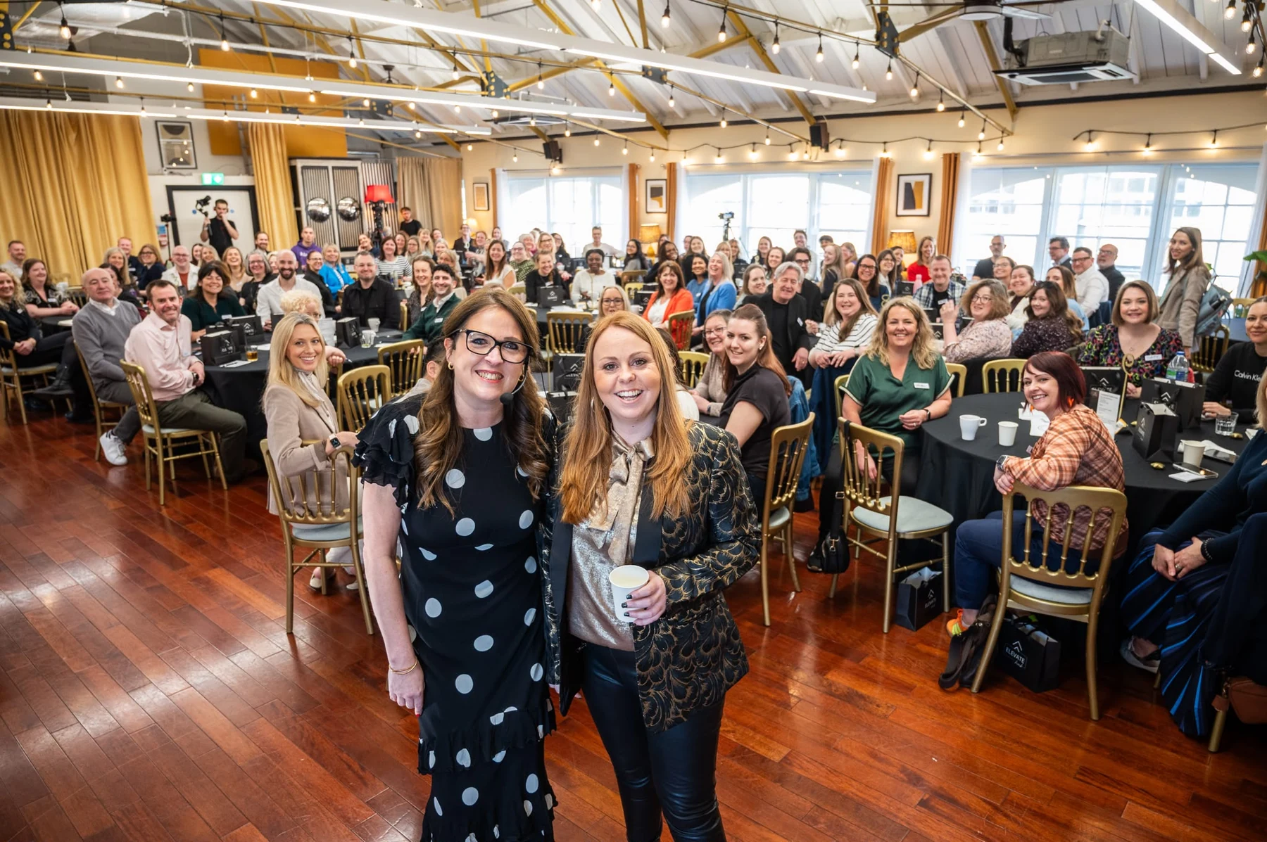 Jess facing the camera with a large event audience behind her